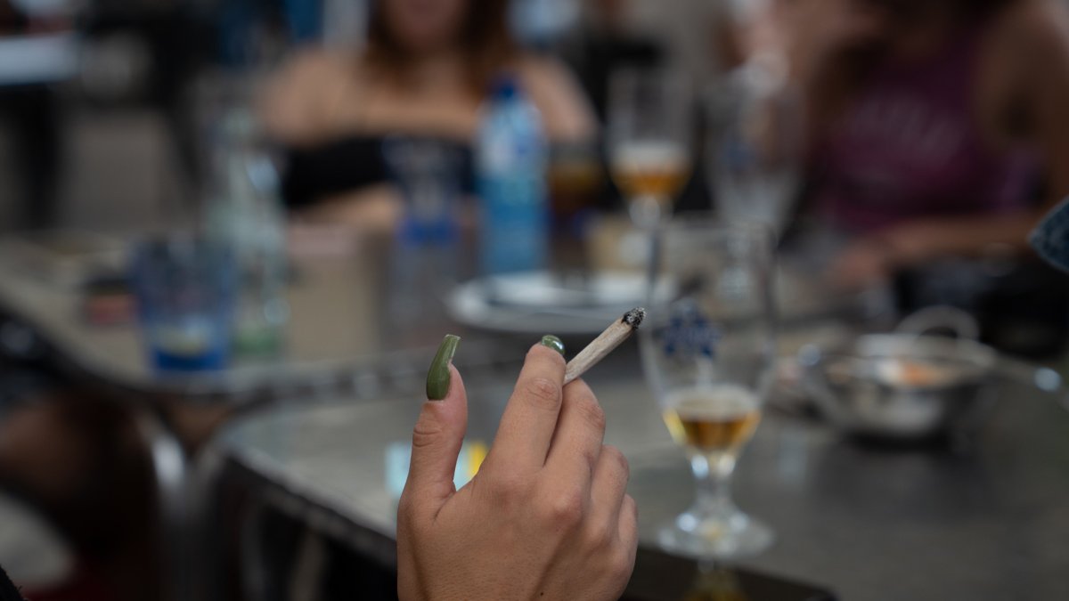 Una dona fuma asseguda a la taula d’una terrassa.