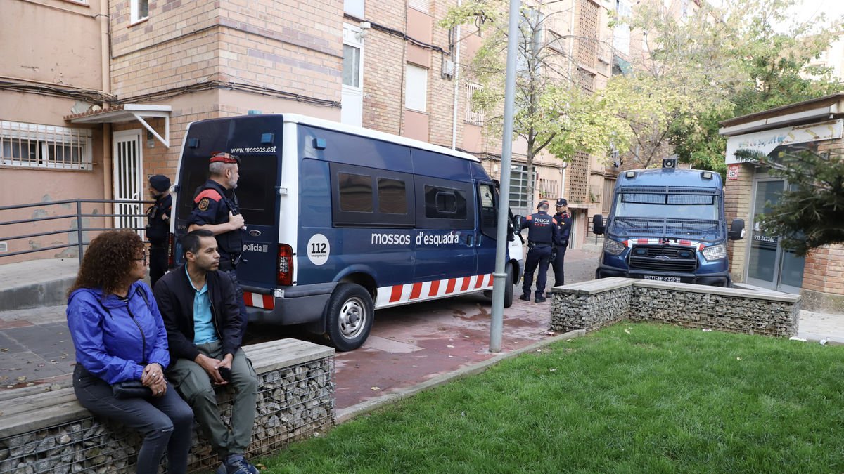 El padre de familia desahuciado, con una activista de la PAH delante de las furgonetas de los Mossos. - MAGDALENA ALTISENT