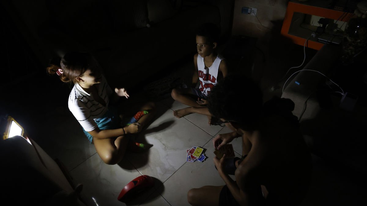 Unos niños juegan a cartas alumbrados por una linterna. - EFE