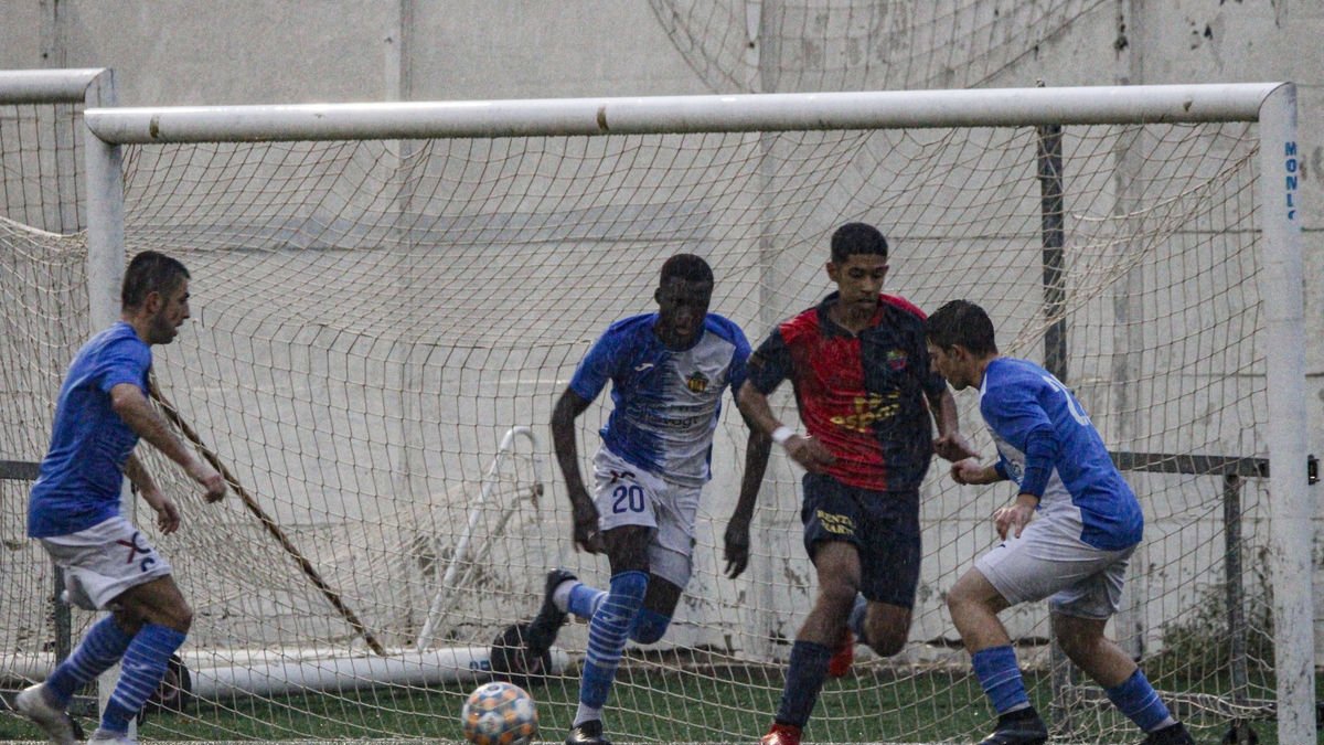 Un jugador del Soses fa una passada pressionat per dos homes de l’Alcarràs B sota una intensa pluja. - ÍNGRID SEGURA