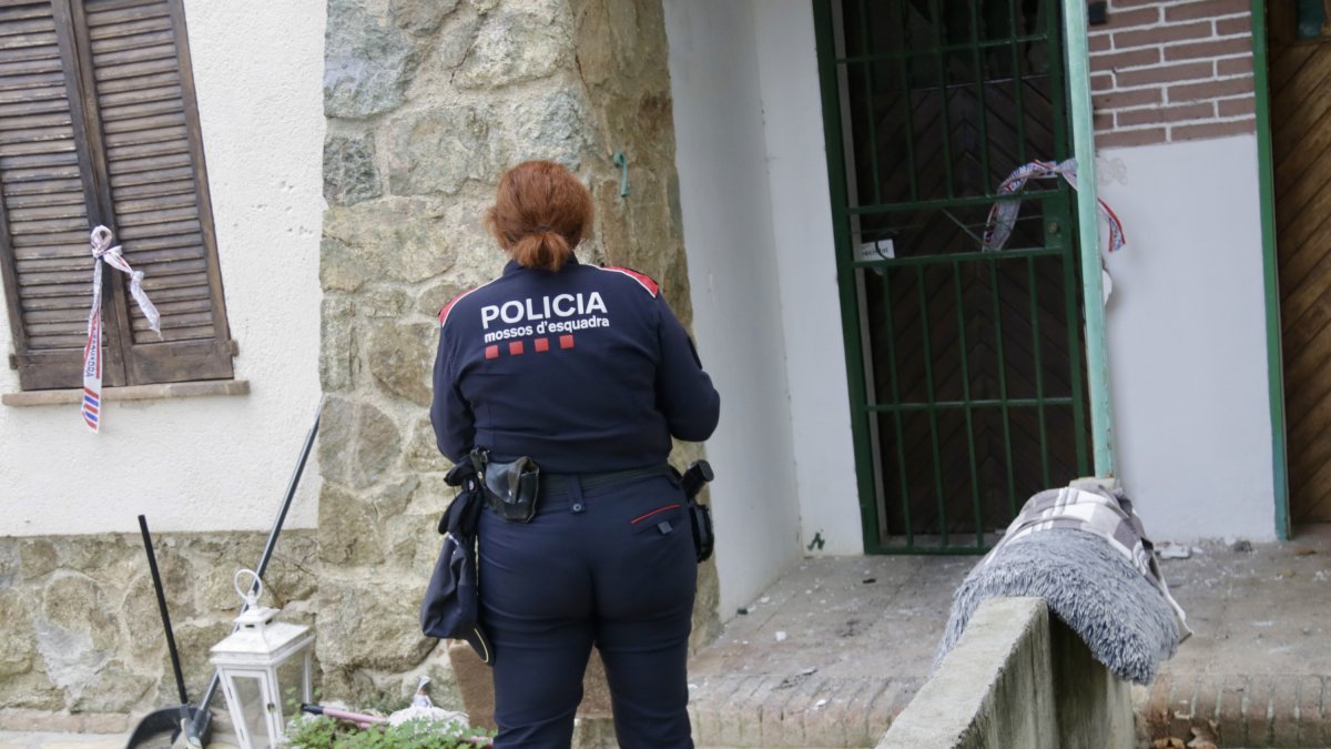 Una agent dels Mossos d'Esquadra davant la casa on han mort un home i el seu fill, a Arenys de Mar