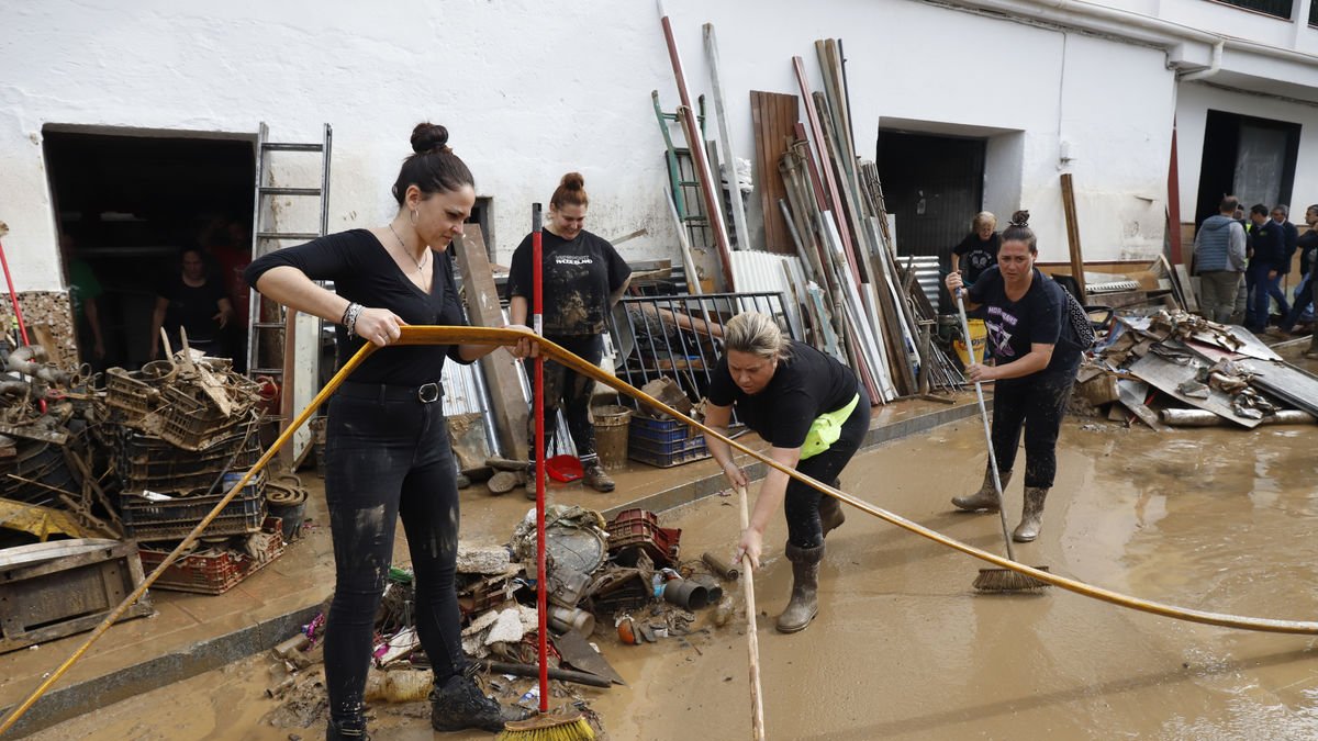 Vecinas de Benargamosa, en Málaga, limpian el barro acumulado en la calle por las fuertes lluvias. - EFE