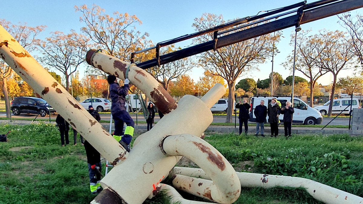 Los operarios cargan las piezas de la escultura en un camión pluma para trasladarla.