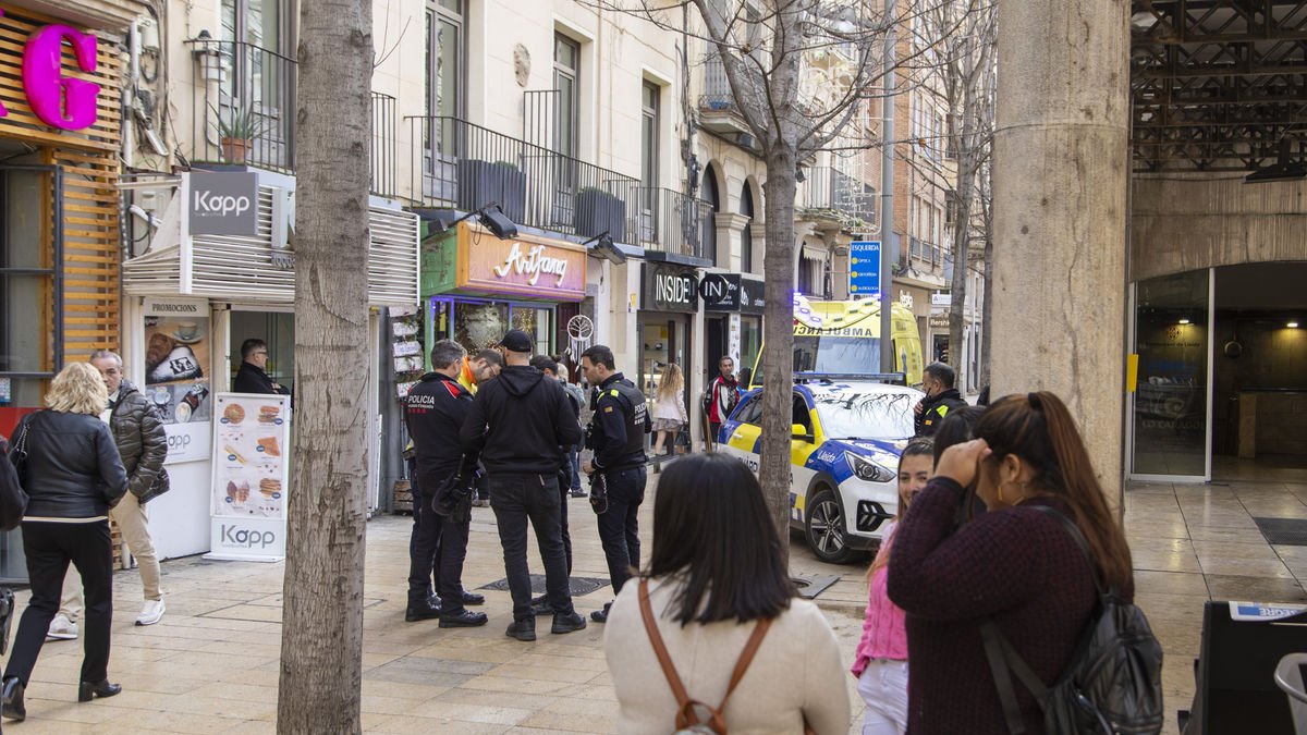 Agentes de la Urbana y de los Mossos, junto a la ambulancia del SEM, ayer en el lugar del asalto. - JORDI ECHEVARRIA