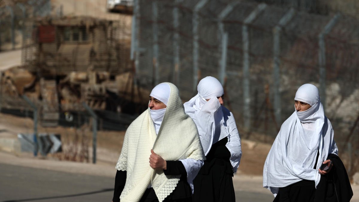 Unes dones caminen al costat de la tanca entre Israel i Síria. - EFE
