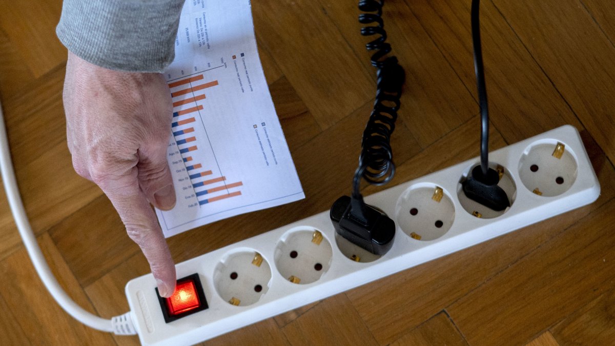Archivo - Un hombre enciende una largadera con varios enchufes con una factura de luz en la mano, a 3 de enero de 2022, en Madrid, (España). El precio medio de la electricidad en el mercado mayorista vuelve a subir hoy, en concreto un 9,88% con respecto a