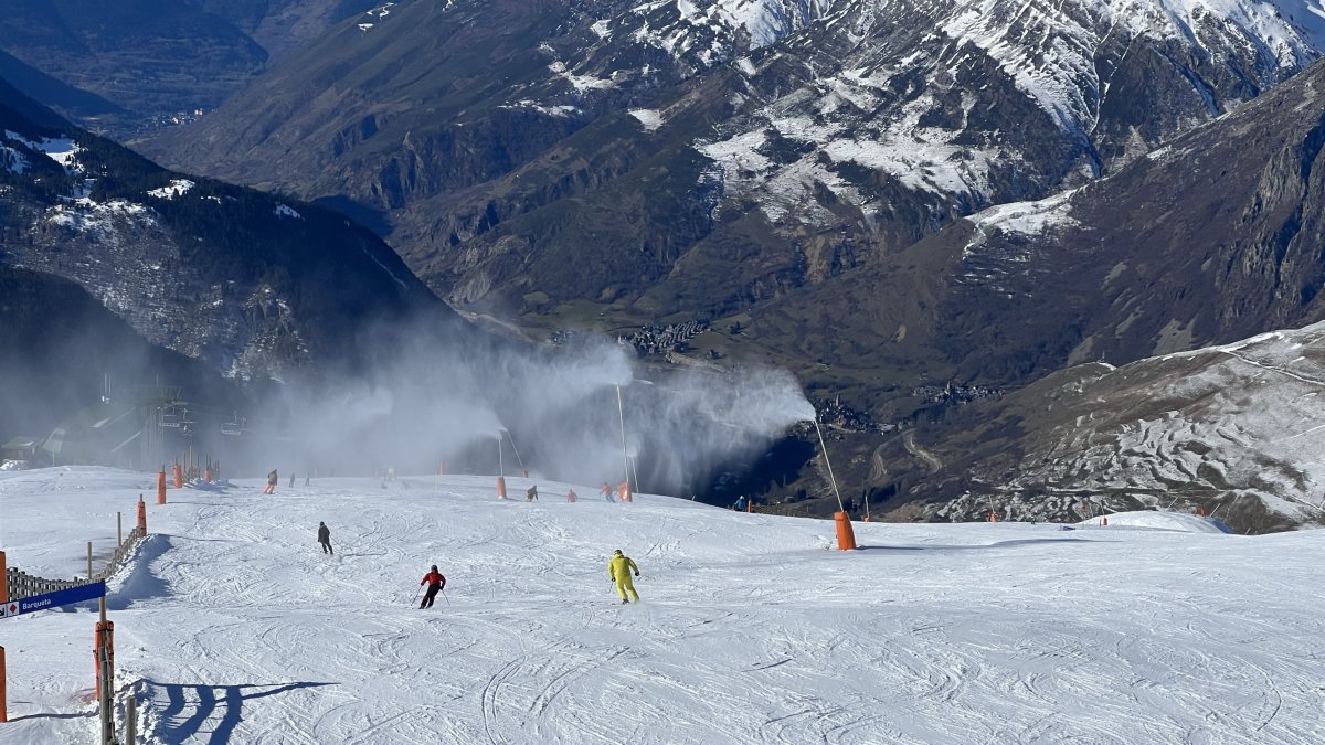 Esquiadors baixant per una pista on funcionen canons de producció de neu a Baqueira.