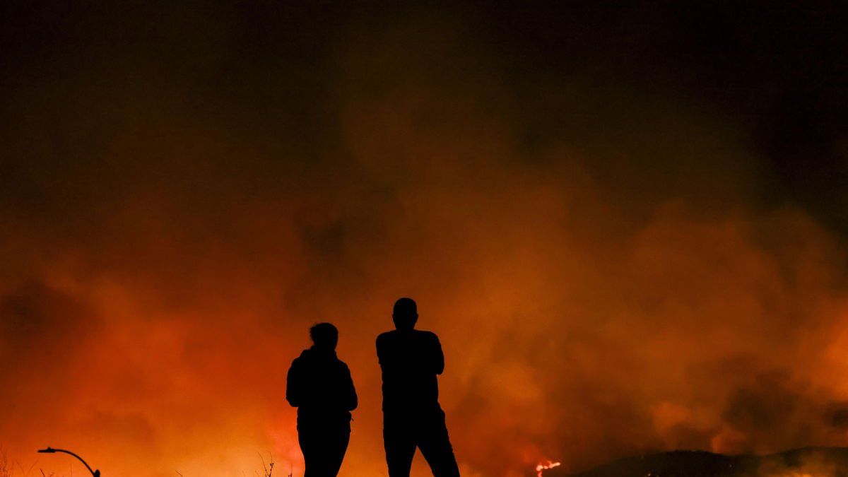 Dos personas miran cómo avanza el incendio de Hugues. - EFE
