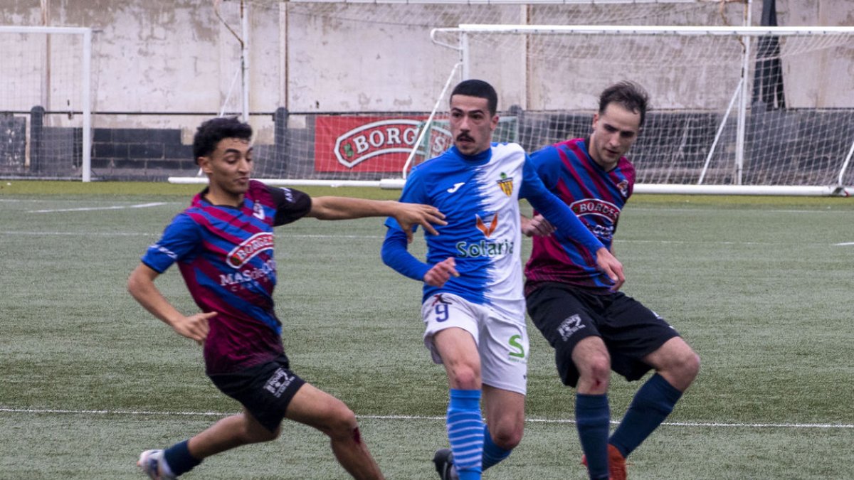 Sánchez pasa el balón ante la presión intensa de dos jugadores locales. - LAIA PEDRÓS