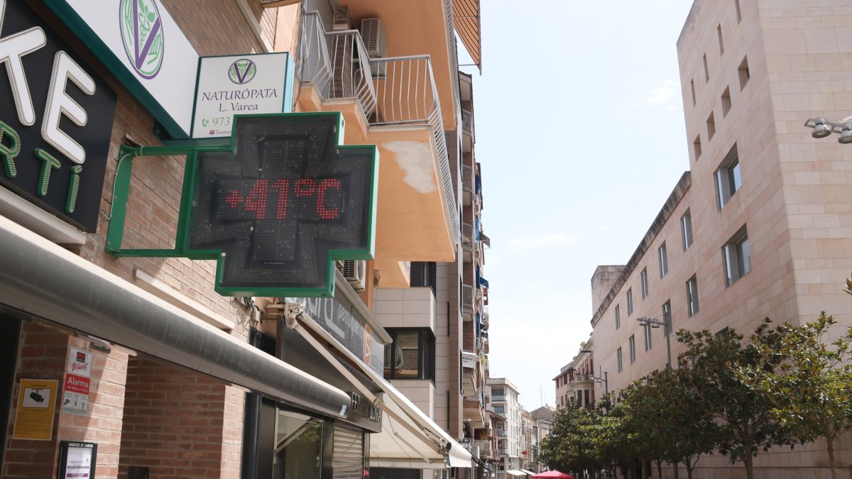 Imagen de la calle de Pino y Cebadilla de Lleida, con gente en la sombra y un termómetro que indica una temperatura superior a los 40 grados.