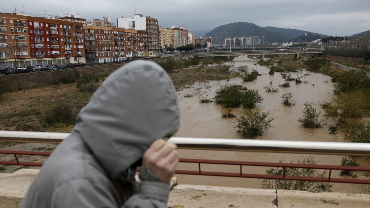 Una persona es protegeix de la pluja mentre travessa un pont. - EFE