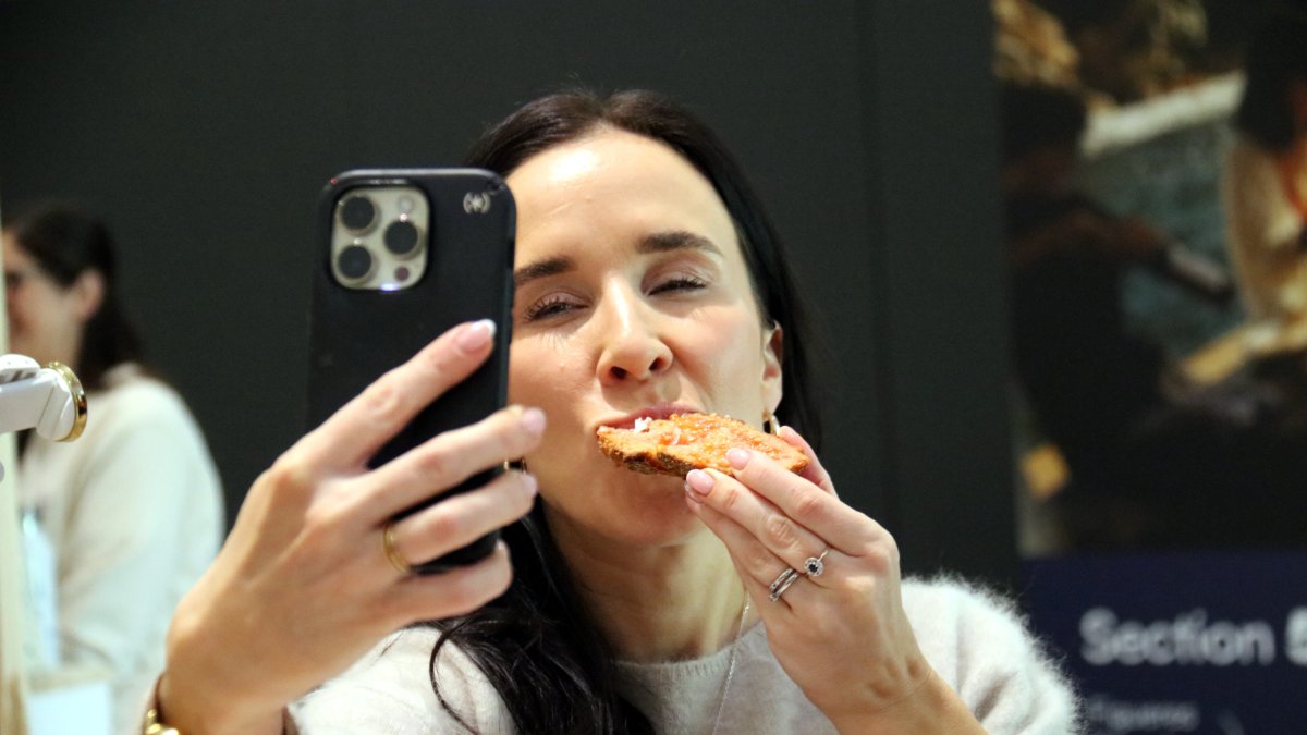 Una influenciadora es fa un vídeo mentre menja pa amb tomàquet.