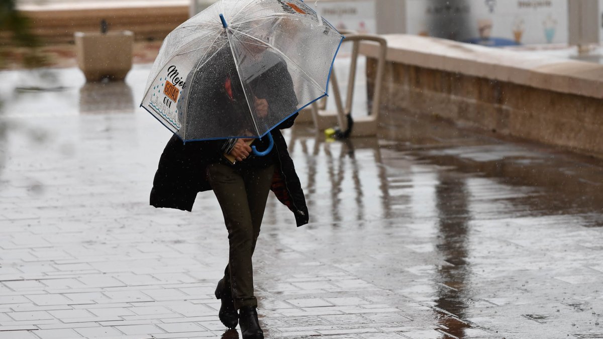 Una persona es protegeix amb un paraigua de la pluja en una fotografia d’arxiu.