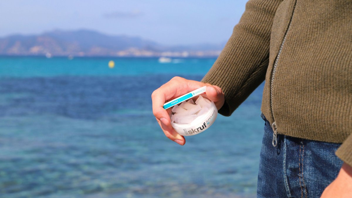 Un hombre muestra una lata con bolsitas de nicotina o snus.