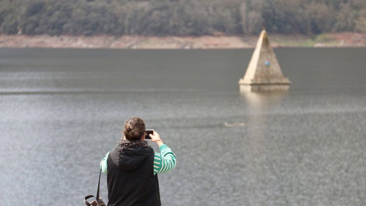 Una mujer fotografía el campanario de la iglesia del pantano de Sau, totalmente sumergida. - ACN