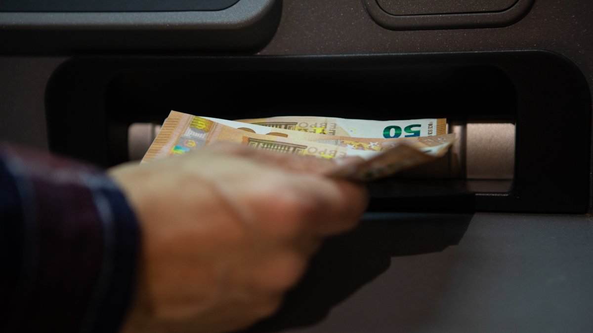 Una persona que retira diners d'un caixer automàtic