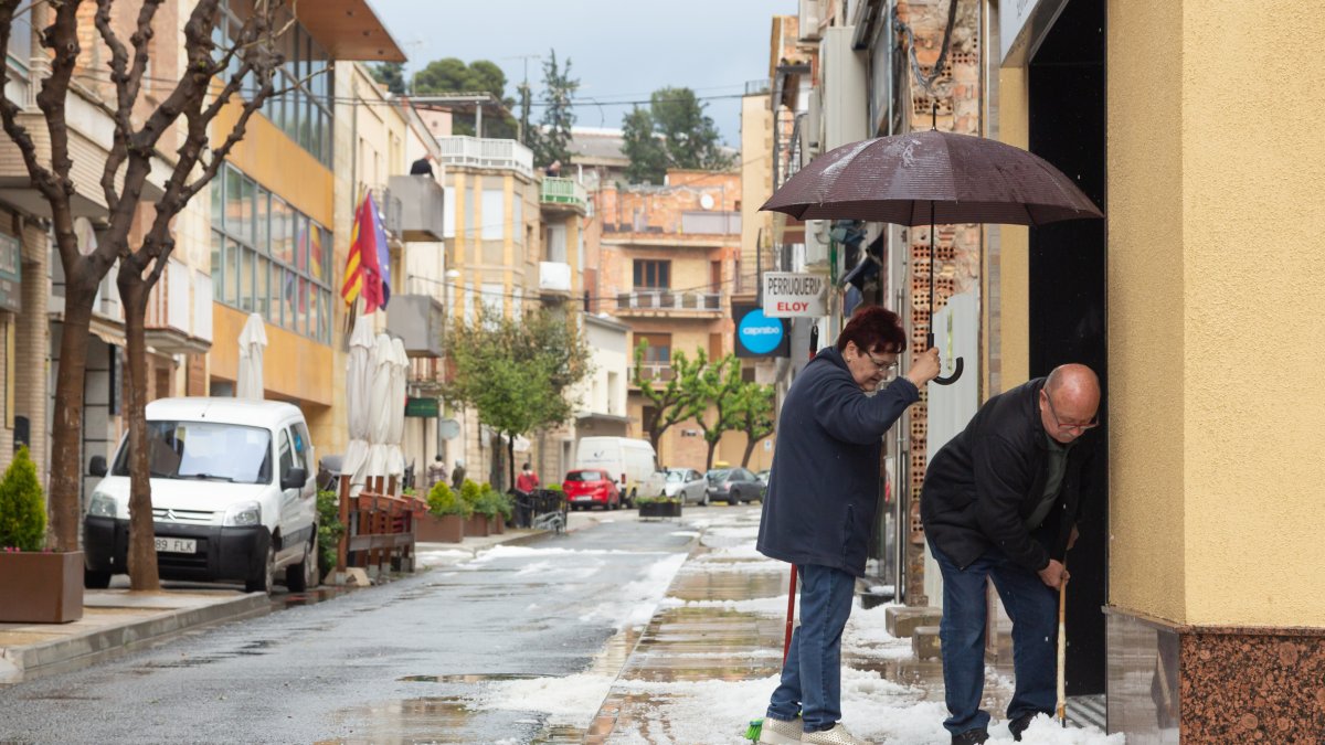 Alcarràs. Dos vecinos de Alcarràs retirando el granizo acumulado delante de su casa.