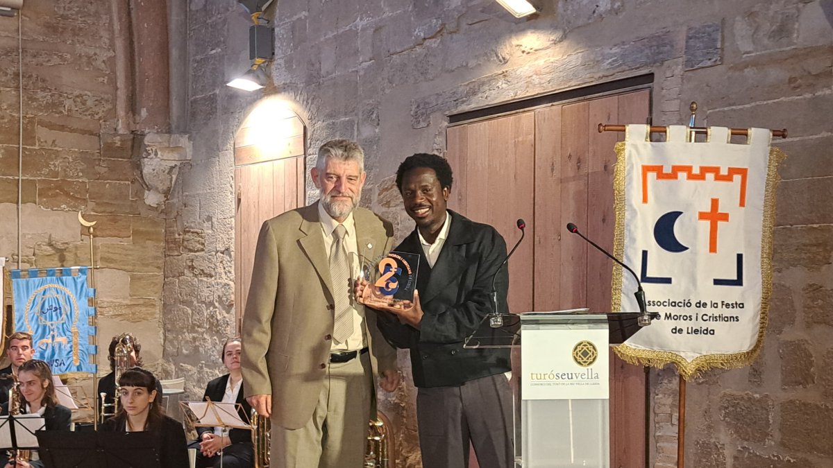 El cantant Kelliy Isaiah, rebent una placa per exercir de pregoner de la festa de la mà de Josep Lluís Gàzquez, president dels Moros i Cristians de Lleida.