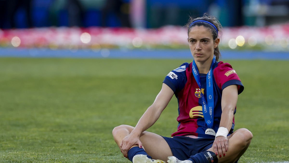 Aitana Bonmatí, sentada en el césped con un claro gesto de tristeza y con la medalla de subcampeona colgada en el cuello, después de que el Barça perdiera la Champions ante el Arsenal. - EFE