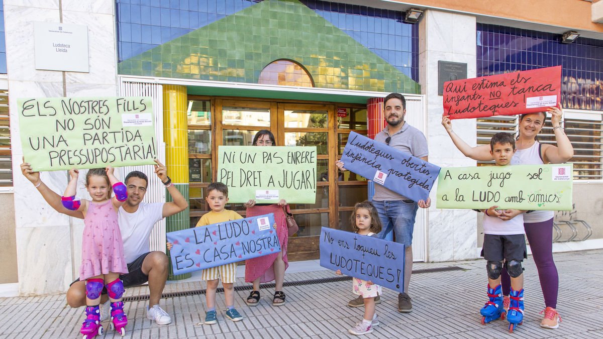 Famílies, davant la ludoteca amb algunes de les pancartes que preparen per a la protesta. - JORDI ECHEVARRIA