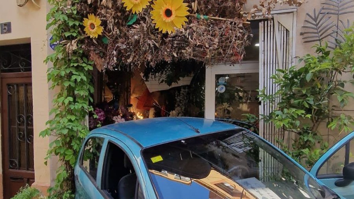 El coche, balizado por la Guardia Urbana, después de chocar marcha atrás contra el escaparate de la floristería