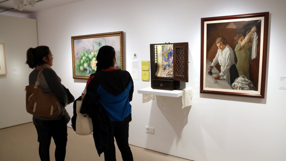 Dues visitants miren la instal·lació 'Amb flors a Maria II' (2018) de Charro Corrales al Museu Morera de Lleida.