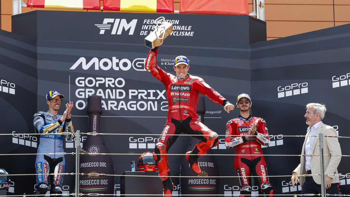 Marc Márquez salta eufòric al podi després de sumar la seua quarta victòria de la temporada en un gran premi, amb Àlex Márquez i ‘Pecco’ Bagnaia aplaudint. - EFE