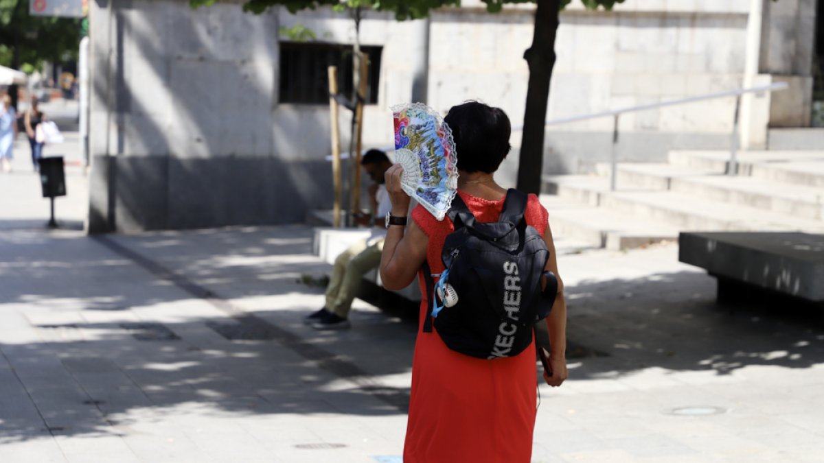 Una vianant es protegeix del sol a Lleida.