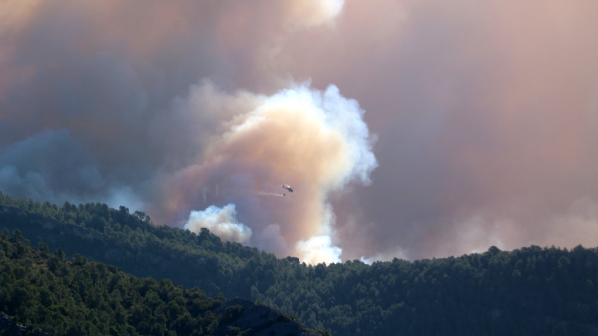 Un helicóptero tira agua en el Valle de Viñas de Paüls hacia donde se ha desplazado el incendio más activo.