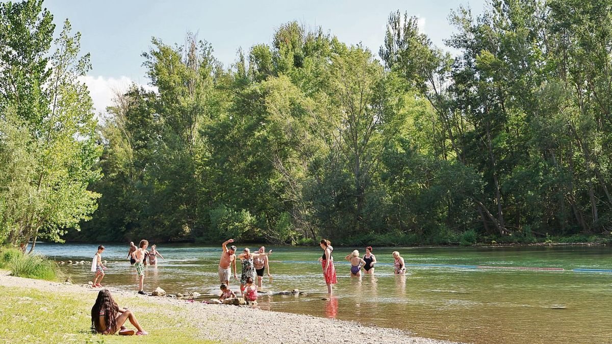 Un grup de banyistes passa la tarda de dijous al curs del riu Segre vora el pont romà de Camarasa.; Array