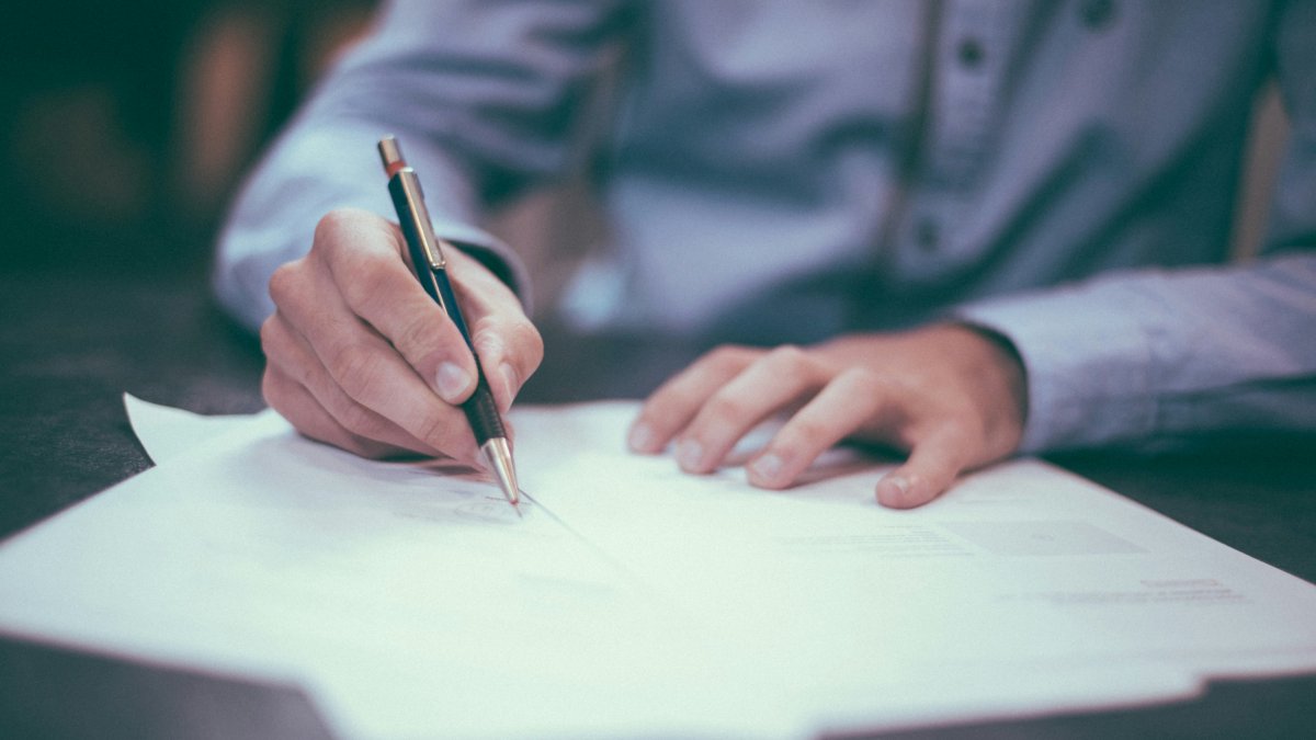 Una persona firmando un documento.