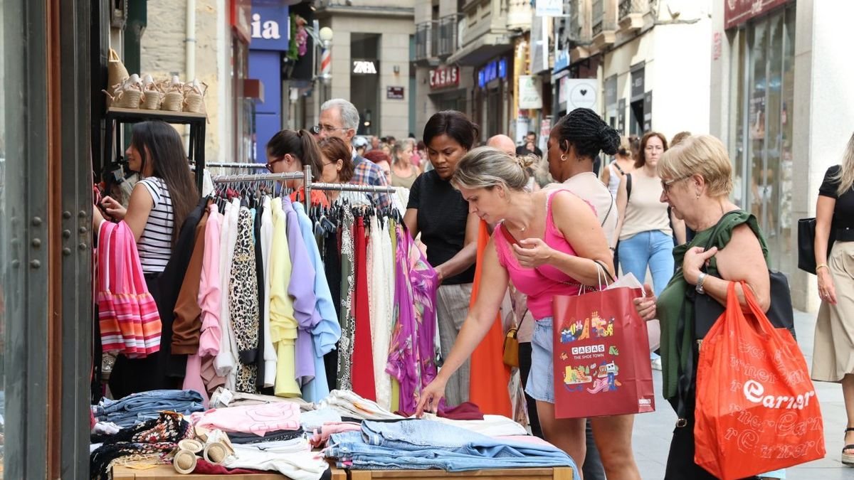 Clientes mirant peces de roba en una parada del Mercat de les Rebaixes de l’Eix Comercial. - AMADO FORROLLA