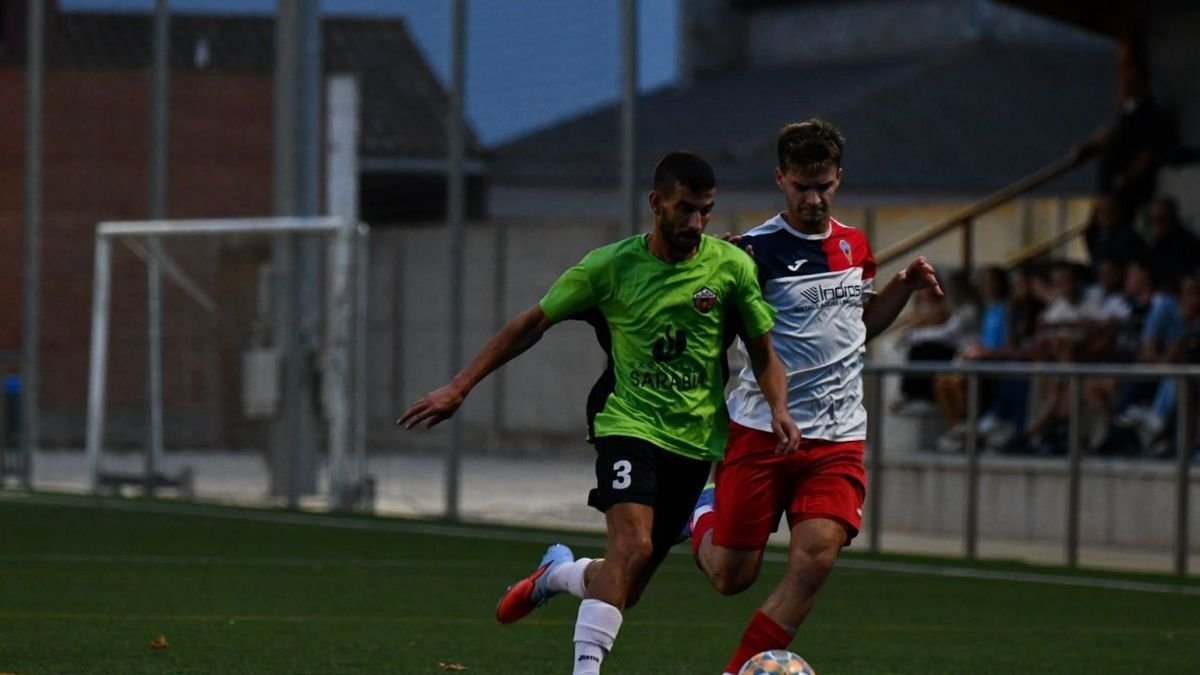 Un futbolista de l’Alpicat avança amb la pilota sota pressió.