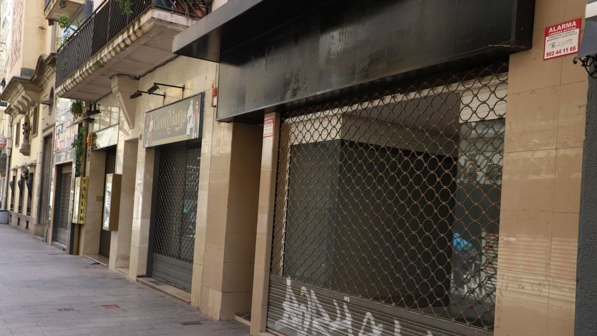 Locales vacíos, con pintadas en la verja, en el Eix Comercial. - MAGDALENA ALTISENT