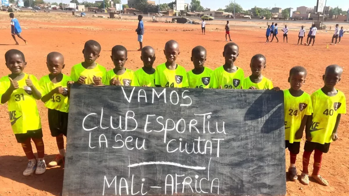 Nens del Centre Djiguiya de Bamako, a Mali, mostren una pancarta de suport al Club Esportiu Ciutat la Seu.