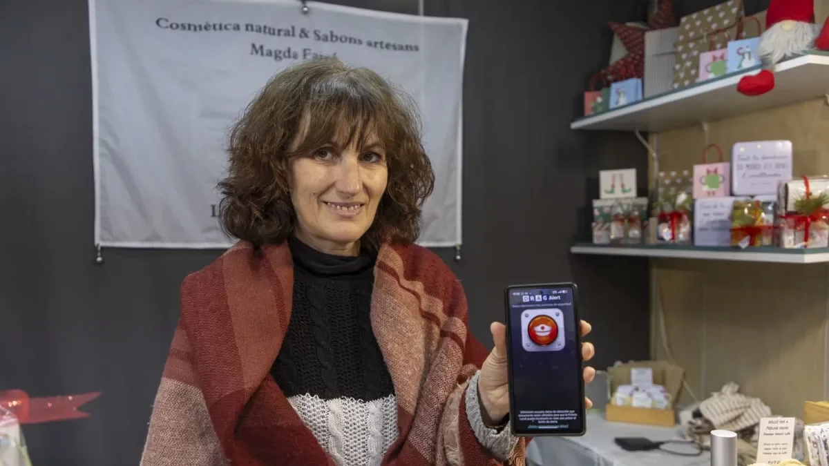 Una comerciante delmercado de Navidad de la plaza Catedral muestra la aplicación DragAlert. - JORDI ECHEVARRIA