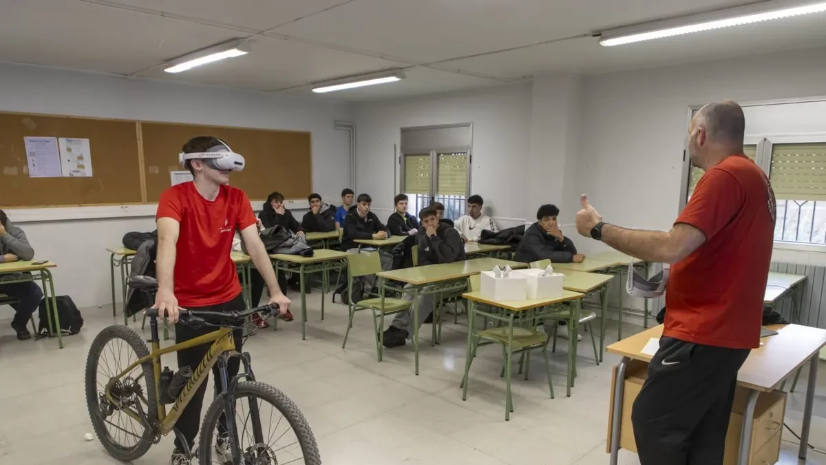 Un alumno con las gafas 3D y la bicicleta atiende en clase las explicaciones del coordinador del proyecto. - JORDI ECHEVARRIA