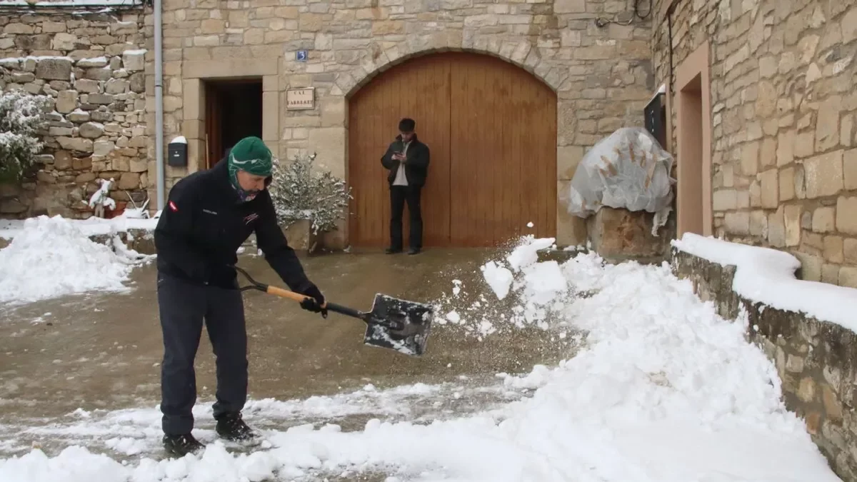 Un hombre quita la nieve de la entrada de su casa en Vimbodí i Poblet. - ACN