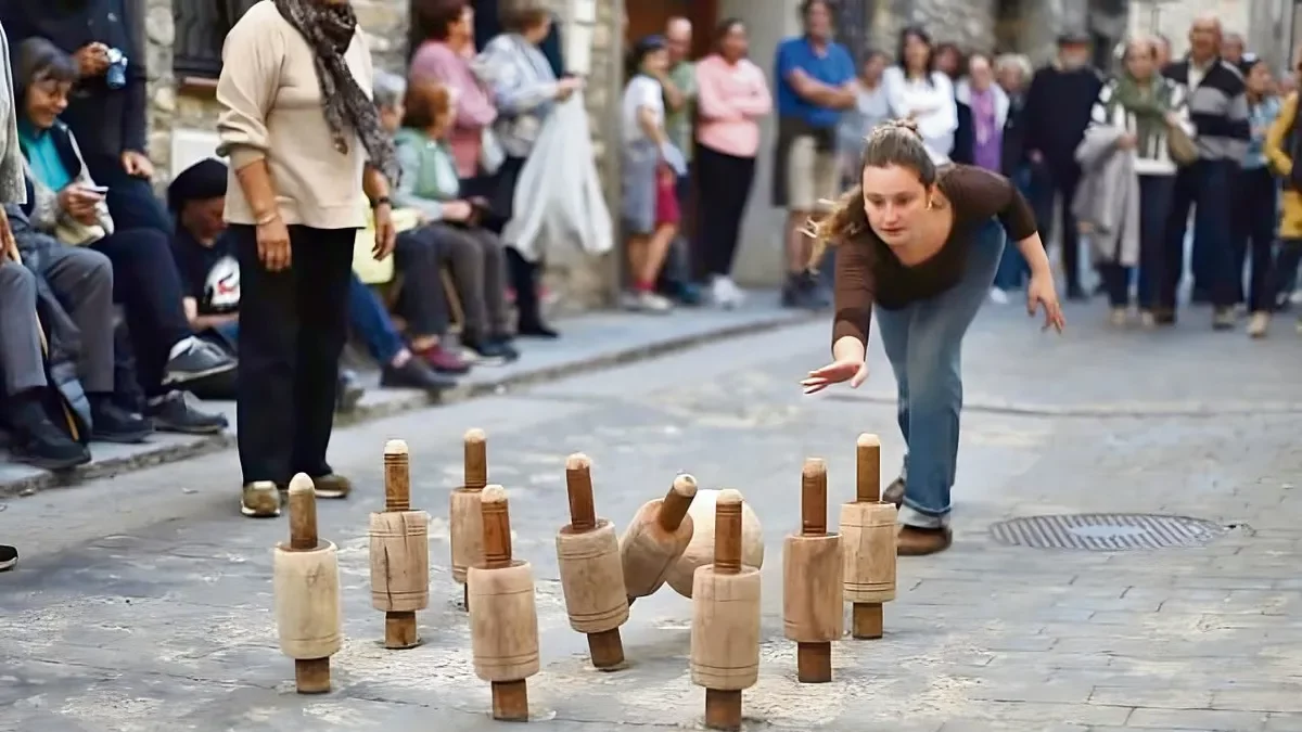 Una joven participa en una partida de ‘bolos de nueve’ en una calle de Campo (Ribagorza). - BIRLLAS CAMPO