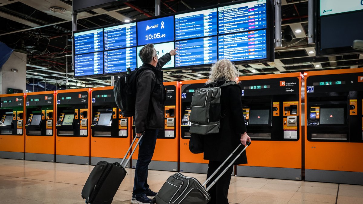 Dos usuaris del tren miren a les pantalles de Sants el dia de la interrupció del servei de
Rodalies.