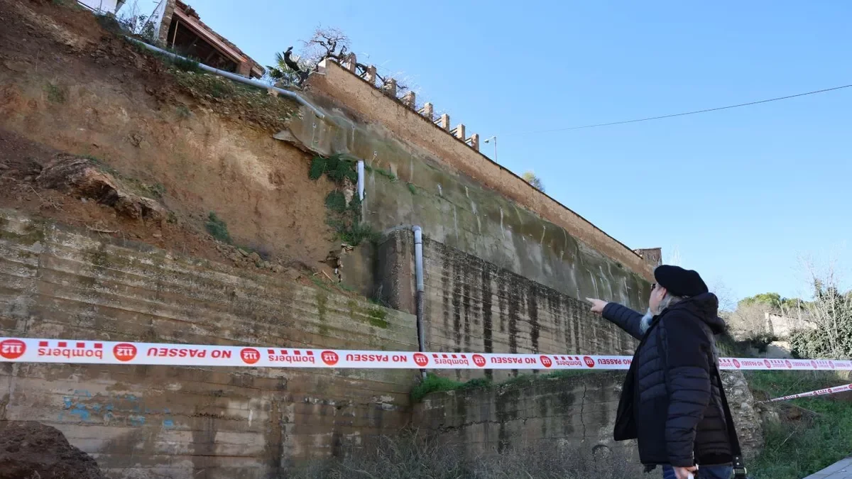 Un veí mira el mur de contenció que va caure a Balaguer. - AMADO FORROLLA
