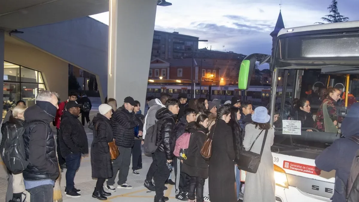 Cues a Tàrrega per pujar a un bus amb un tren parat al fons per la caiguda del centre de control d’Adif. - JORDI ECHEVARRIA