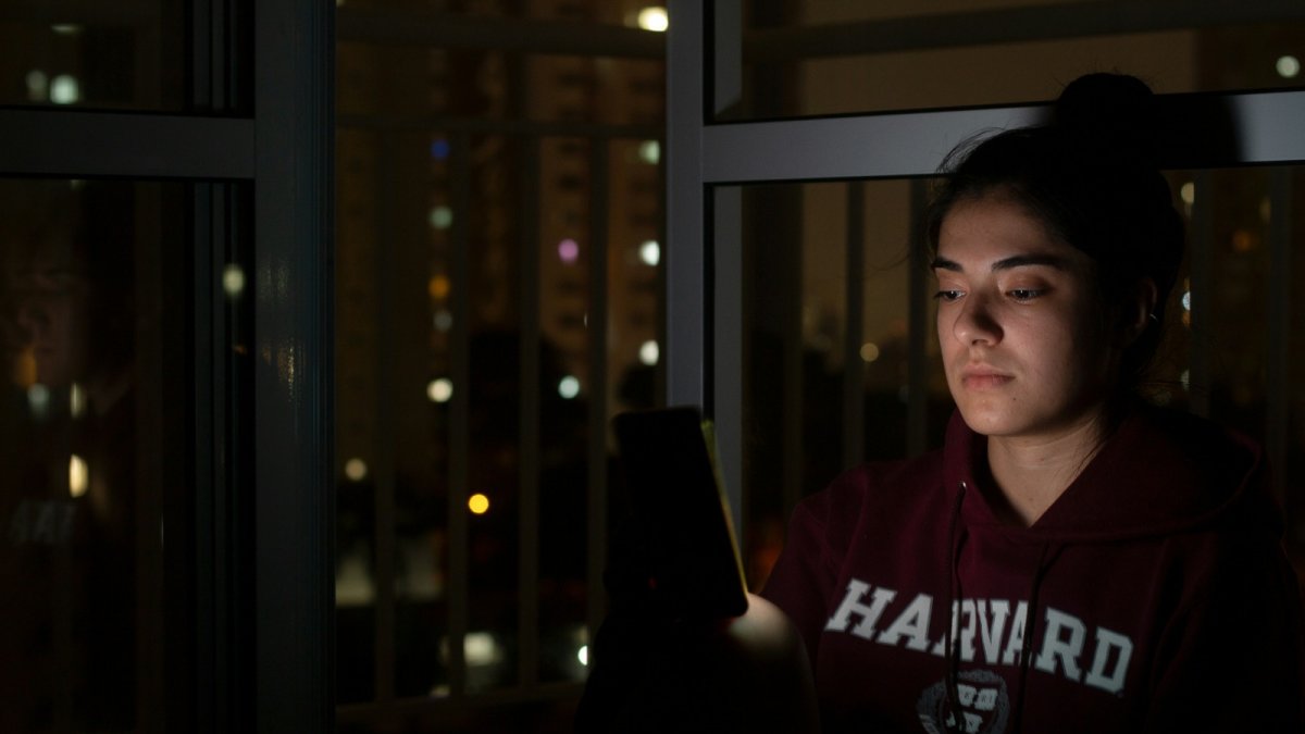 Una dona amb un dispositiu electrònic de nit.