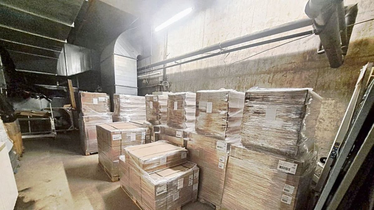 Imatge dels palets amb menjar, llits i estris de lavabo personal en un magatzem. A dalt a la dreta, anvers i revers d’una bossa amb una ració de menjar. - SCD