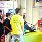 Joves jugant a un videojoc en una fira.
