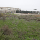 Vista de los terrenos donde está previsto el nuevo centro comercial, con el instituto Joan Oró y el Camp Escolar al fondo.