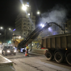 Una màquina retira l’asfalt d’avinguda de Madrid mentre passen dos vehicles pel carril obert encara al trànsit, ahir a la nit.