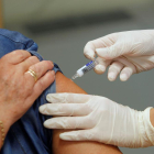 Una infermera posa una vacuna contra la grip.
