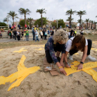 Dos jóvenes colocan cruces de tela amarillas en la playa de Mataró, en una iniciativa del Comitè de Defensa de la República.