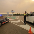 Mossos d’esquadra es protegien ahir de les cendres amb màscares per informar els conductors del tall de la carretera C-12 a Maials.